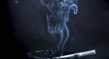 smouldering cigarette in an ashtray, with smoke wafting upwards