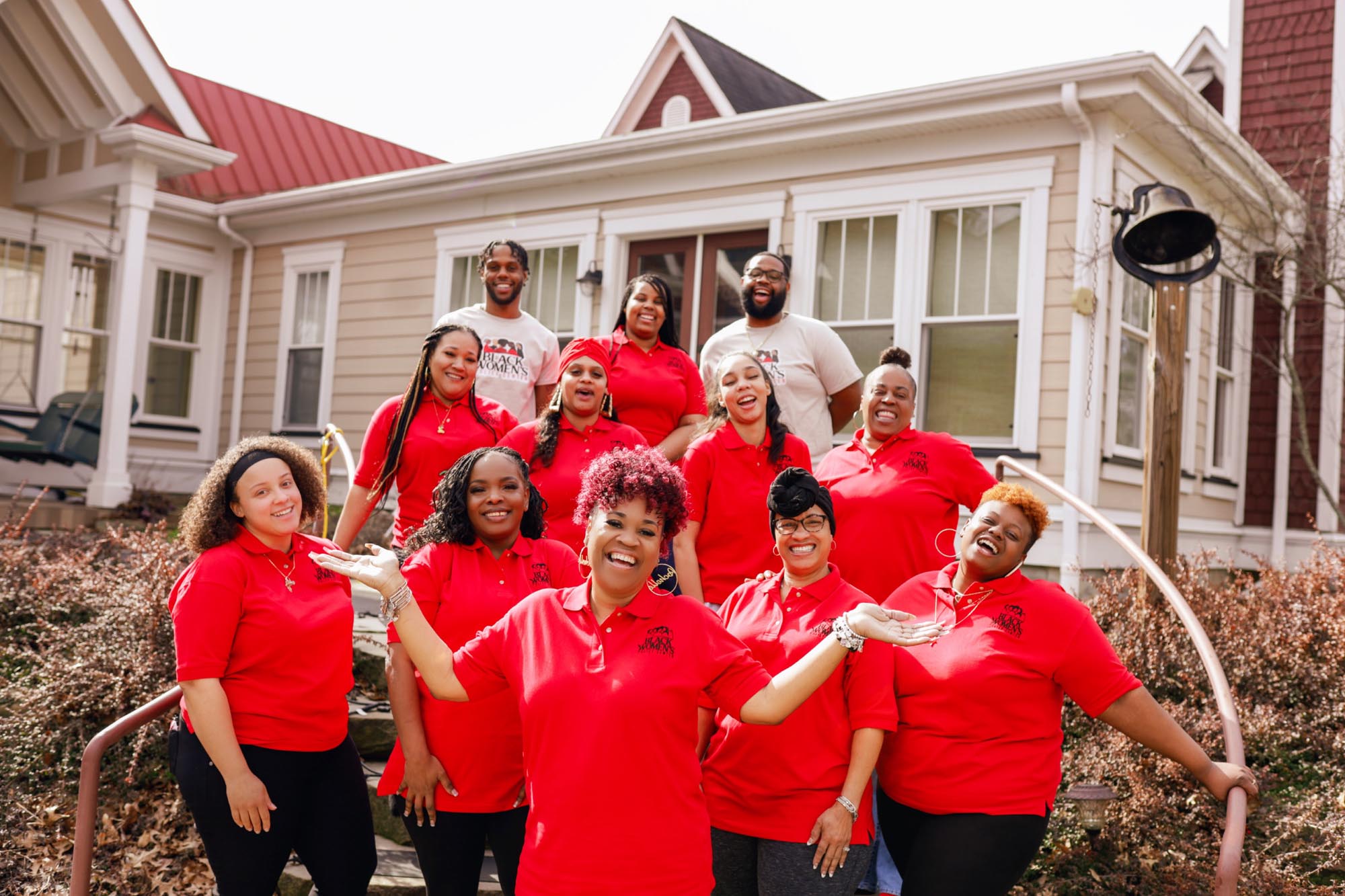 a group of black women and two men wearing red shirts smiling
